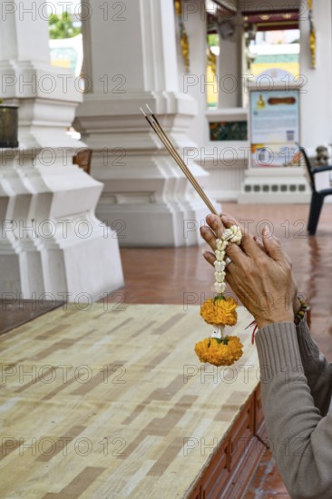 Bangkok, Thailand. February 20th 2025. A Thai visitor prays and makes an offering at The Wat Suthat Thepwararam Temple, Bangkok