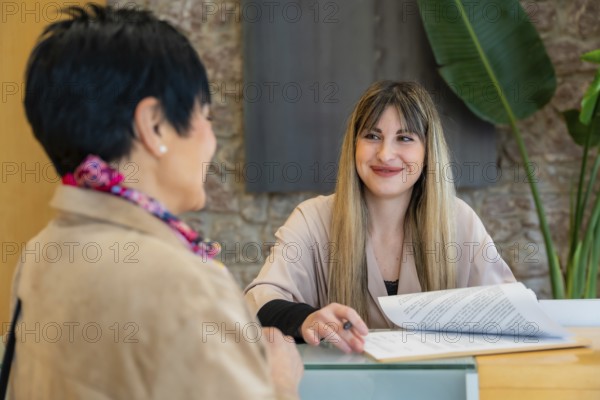Client having a consultation with a smiling blonde receptionist, filling out documents and discussing services at a modern aesthetic beauty center reception desk