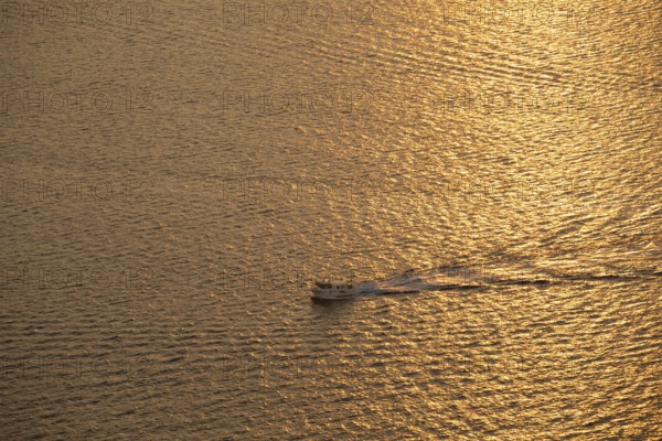 A small boat glides through the shimmering golden waters of the Mediterranean Sea at sunrise, capturing the serene beauty of the Costa Blanca's tranquil coastal landscape