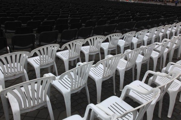 White plastic chairs standing in rows, seating at an open-air event, empty, vacant