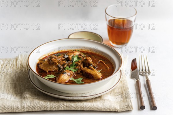 A bowl of traditional Georgian chicken stew, chakhokhbili, garnished with fresh coriander. This hearty dish is rich with paprika and simmered in a flavorful tomato sauce