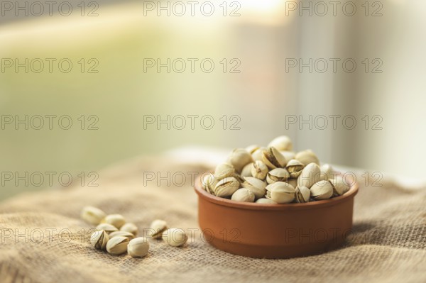 A warm image showcasing a bowl of pistachios on a burlap surface, with a soft focus background. Ideal for themes of health, nutrition, and natural snacks