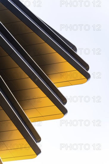 Abstract view of modern architectural design featuring striking golden panels set at angles against a clear sky, capturing a blend of geometry and vibrant color