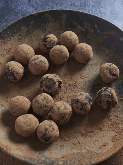 Energy balls. Raw chocolate bliss balls dusted with cacao on a dark plate
