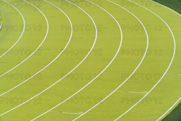 A vibrant aerial shot of a freshly marked bright green running track at an outdoor athletics stadium featuring distinctive white lines and curves