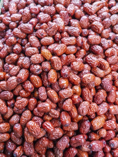A vibrant close-up view of glossy, red jujube fruits, freshly harvested and displayed for sale at a local market in Singapore