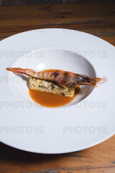 Juicy grilled prawn served on a bed of herb-seasoned egg terrine, accompanied by a flavorful orange sauce. A sophisticated gourmet dish with a rich blend of flavors