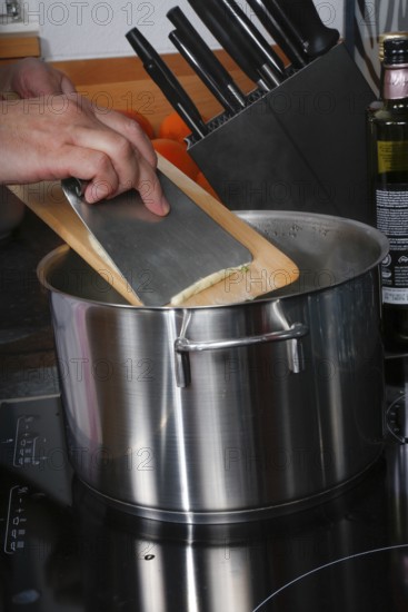 Swabian cuisine, preparation of herb spaetzle for roast beef, scraping spaetzle, spaetzle board, dough, cooking pot, savoury, salty, typical Swabian, home cooking, traditional cuisine, men's hands, food photography, studio, Germany