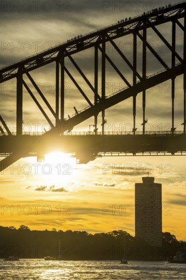 Tourists climbing Sydney harbour bridge at sunset, Sydney, New South Wales, Australia