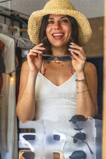 Happy tourist wearing straw hat trying on sunglasses in a souvenir shop in siargao island, philippines