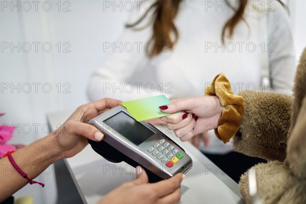 A client at a beauty salon completes a payment transaction by tapping a card on a device. The atmosphere is professional and inviting, enhancing the salon experience