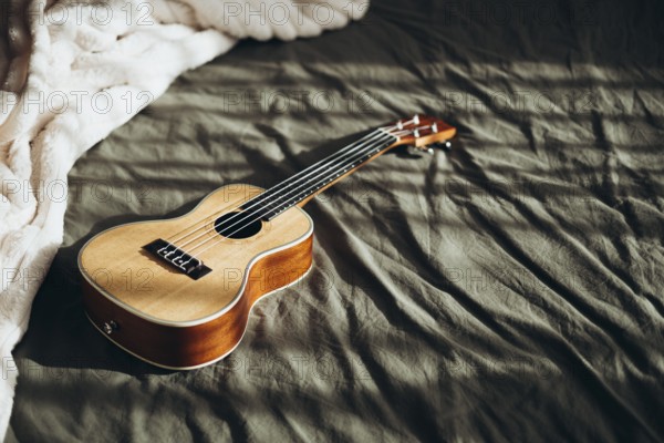 A wooden ukulele lies on a textured bedspread, illuminated by gentle natural light The warm tones of the instrument contrast with the soft, cozy background