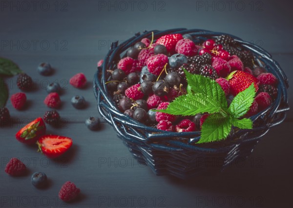 Mix of fresh berries, in a basket, on a wooden gray table, no people, top view