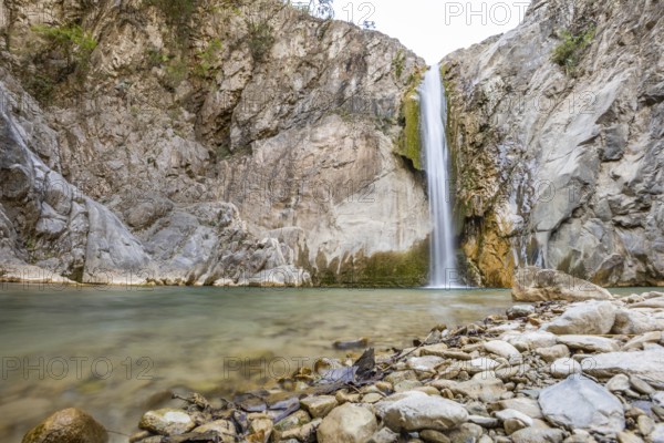 Scenic waterfall cascades into a tranquil pool surrounded by rugged rocks in Matacanes, Nuevo Leon, Mexico. The serene setting contrasts with the canyon's rough terrain