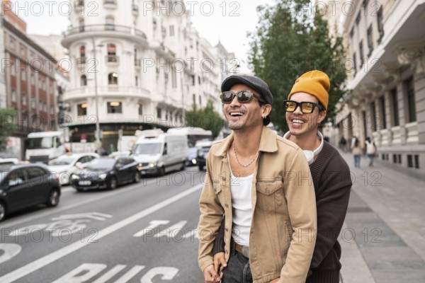 A joyful colombian gay couple enjoying a casual city walk. Both are wearing sunglasses and showcasing happiness and connection against an urban backdrop of architecture and vehicles