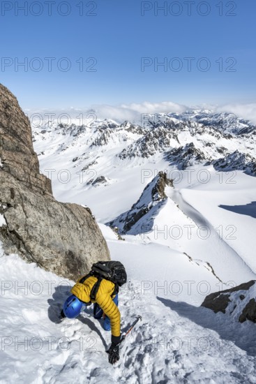 Mountaineer with ice axe and crampons, ascent through steep snowfield to Piz Kesch or Piz d'Es-cha in winter, view of mountain panorama with Vadret da Porchabella glacier, Albula Alps, Rhaetian Alps, Grisons, Eastern Switzerland, Switzerland