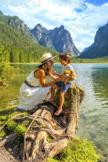Mother and son sharing a playful moment by an alpine lake, surrounded by the breathtaking scenery of the dolomites