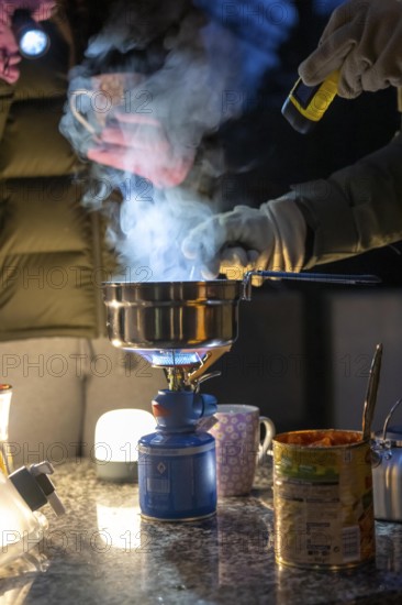 Symbolic picture blackout, extensive, prolonged power failure, in private surroundings, without electricity, heating, water, cooking, heating food and water with a gas-powered camping stove, on the balcony