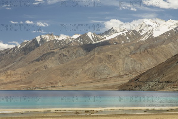 Beautiful view of Pangong Tso lake in Ladakh, India, with its brilliant blue waters set against the background of the majestic snow-capped Himalayan mountains under a clear sky