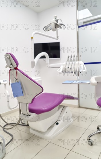 Bright and clean dental clinic room featuring a modern dental chair, overhead light, and essential tools, designed for patient comfort and effective dental procedures