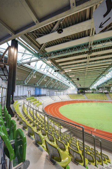 Interior view of an empty stadium with green rows of seats and an athletics track, Glaspalast, Sindelfingen, Germany