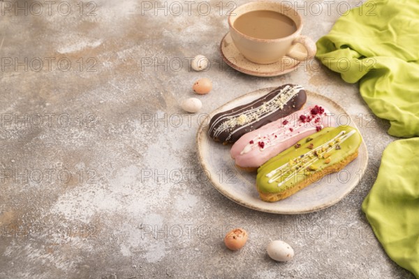 Glazed Eclairs on brown concrete background and green linen textile, cup of coffee, side view, copy space