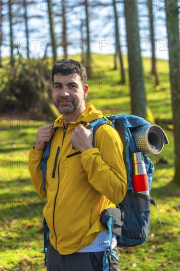 Male hiker carrying a backpack, enjoying a sunny day in the forest while trekking through the vibrant landscape on his adventure