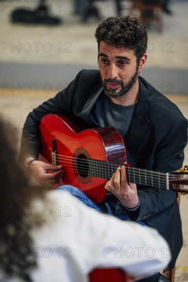 From above male friends playing guitars at table in music studio