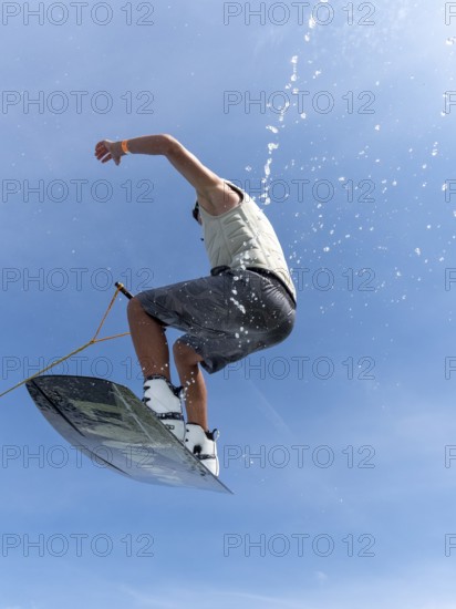 Young man jumping and flying with wakeboard, water sports and water skiing in the wakepark