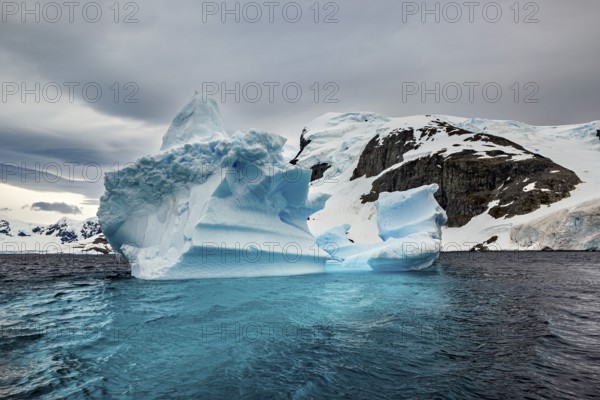 Large iceberg in the cold sea with snow-covered sky and dramatic atmosphere, icebergs in the Southern Ocean in Antarctica