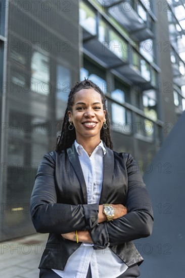 Vertical portrait of a proud latin businesswoman smiling with arms crossed standing in the city