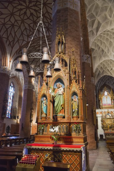 Gothic altar in a church with ornate figures of saints and candle lighting, St Jakobi Church, Olsztyn, Allenstein, Warmia-Masuria, Poland