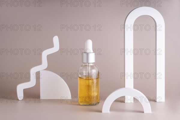 A modern cosmetic serum bottle with a silver dropper surrounded by minimalist geometric shapes on a soft beige background creates a stylish and elegant composition