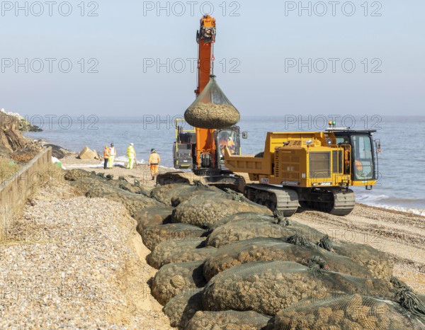 Emergency coastal defences work placing rock bags on beach to protect property, North Sea coast, Thorpeness, Suffolk, England, UK