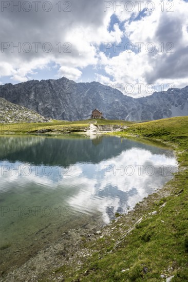 Rocky mountain peaks of the Panargenkamm and mountain hut Neue Reichenberger Hütte, mountain lake Bödensee with reflection, Lasörlinggruppe, Hohe Tauern National Park, East Tyrol, Austria