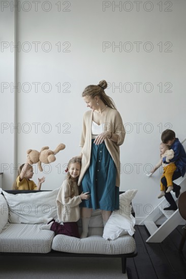 A joyful family scene with a mother and four children playing in a cozy living room The children are engaged in playful activities, creating a warm and loving atmosphere