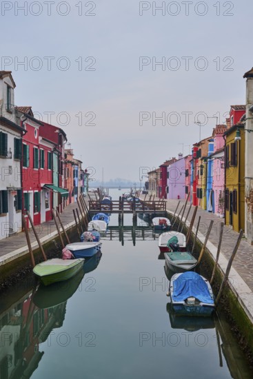 Colorful houses beside the waterway in between 'Fondamenta Cao di Rio a Sinistra' and 'Fondamenta Cao di Rio a Destra' with boats lying in the water on the island of Burano, Italy