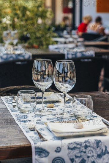 Set of glasses with white wine and plates placed on table with tablecloth on table