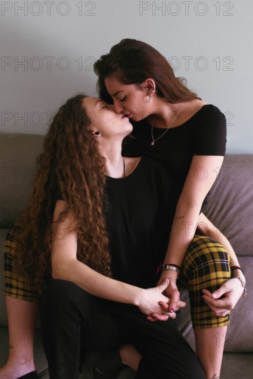 Two women, a female gay couple, share a loving kiss, intimately engaged in the moment. This warm scene captures their bond