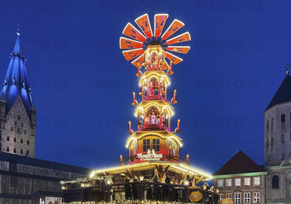 Christmas market with mulled wine pyramid on the market with St. Ulrich Cathedral and Gaukirche in the evening, Paderborn, North Rhine-Westphalia, Germany