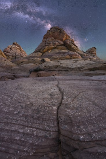 Captivating image of rugged desert rock formations beneath a vibrant Milky Way in Coyote Buttes, Arizona. The clear night sky enhances the texture and depth of the weathered landscape