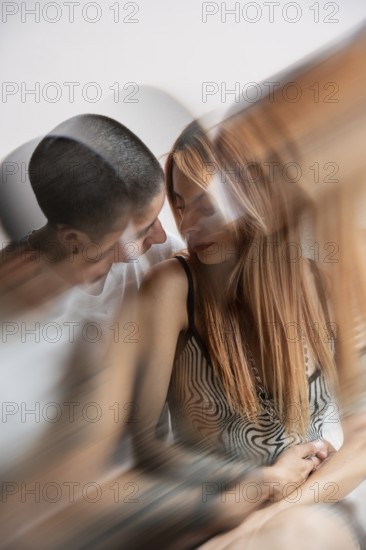 A tender, intimate moment between two lesbian women, one with short hair and the other with long, red hair, sharing a quiet connection. The blurred effect adds a dreamy quality