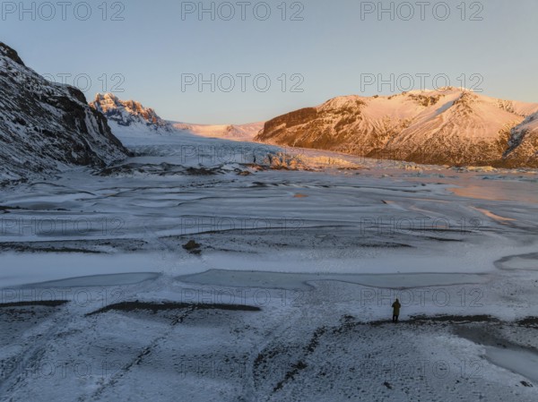 A breathtaking Icelandic winter scene features serene frozen landscapes and sunlit Skaftafell mountains. This tranquil setting captures nature's raw beauty in soft light