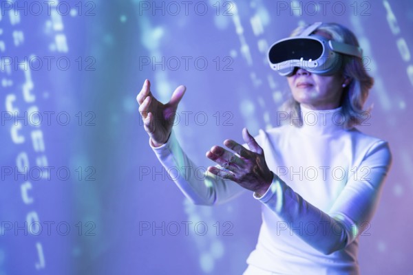 Elderly Asian woman wearing a virtual reality headset, interacting with the digital elements of the metaverse. The scene is illuminated by blue light, indicating a futuristic setting