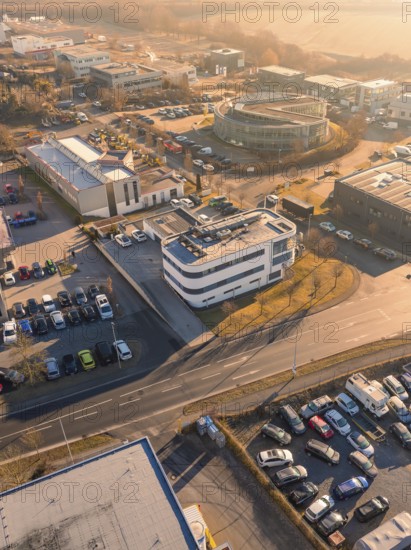 Aerial view of an urban industrial area with buildings and car parks under an orange sky, Gültstein, Herrenberg, Germany