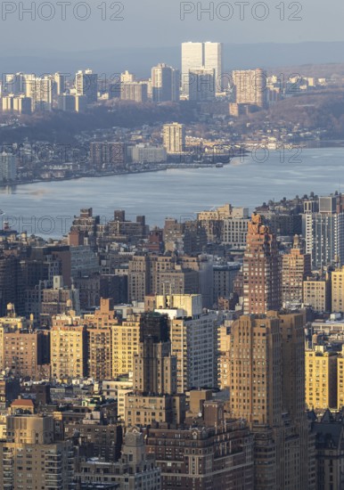 Top view of New York City during sunset, showcasing a panoramic view of buildings bathed in golden light with the Hudson River and New Jersey in the background