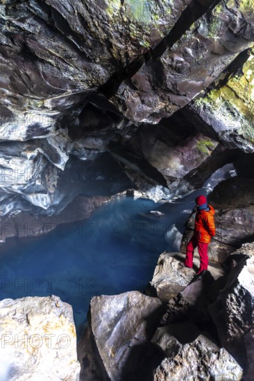 A man in the Grjotagja volcanic cave with hot thermal water near Lake Myvatn, Iceland