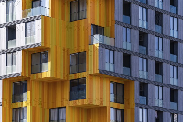 A striking example of modern architecture utilizing a mix of glass, concrete, and metal, featuring vibrant yellow panels against a gray backdrop in a suburban setting