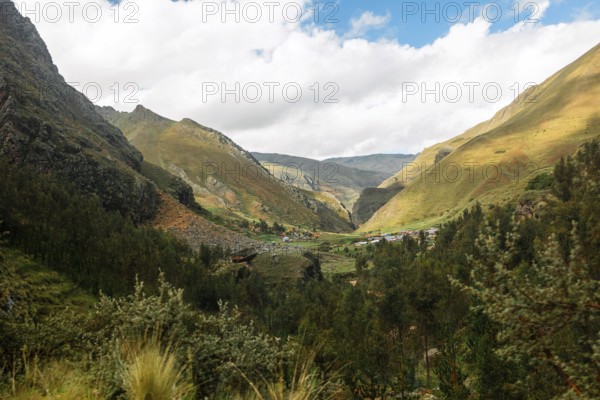 This image captures a breathtaking view of a green and fertile valley nestled in the Peruvian Andes