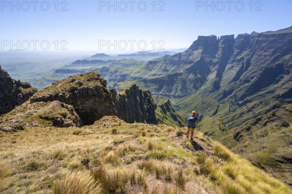Young hiker looking at the impressive mountains and cliffs of the Drakensberg Mountains, hiking trail on the Sentinel Hiking Trail, Drakensberg, KwaZulu-Natal, South Africa